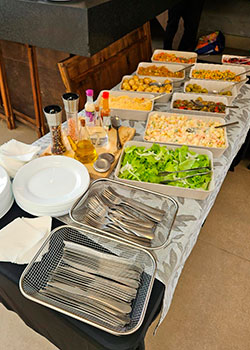 Mesa com saladas, batatinhas, molhos e pratos no serviço de Buffet Churrasco Prata