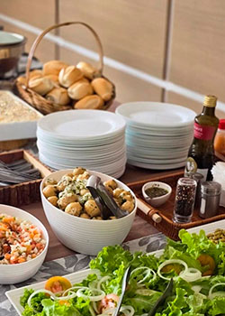 Mesa com saladas, pães e acompanhamentos do Buffet Churrasco Padrão