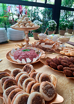 Mesa com esfiha, kibe cru e pães sírios em buffet árabe para eventos